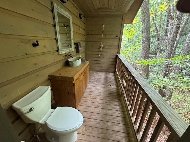 exterior space featuring vanity, wooden walls, wood-type flooring, wooden ceiling, and toilet