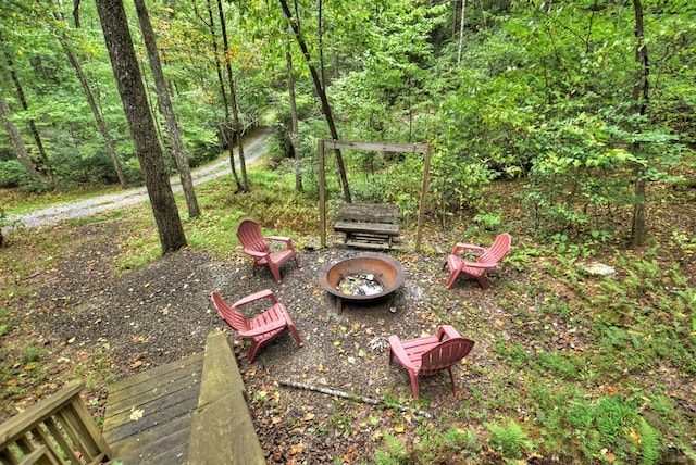 view of yard featuring a view of trees and an outdoor fire pit