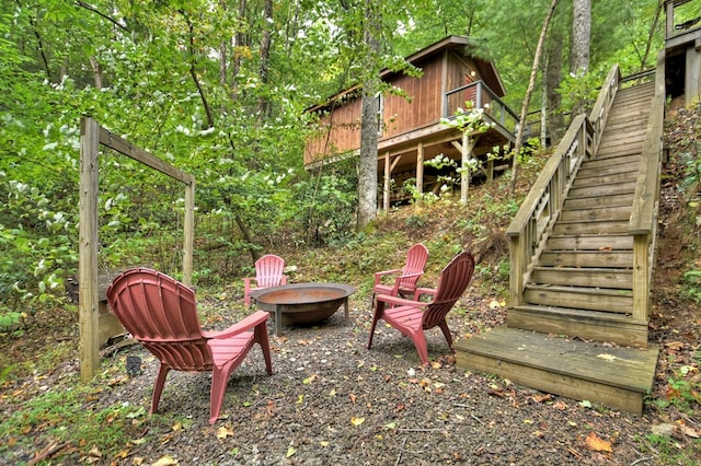 view of yard featuring an outdoor fire pit, stairs, and a view of trees