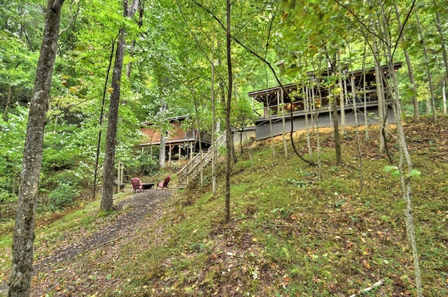 view of yard featuring a deck, stairway, and a view of trees