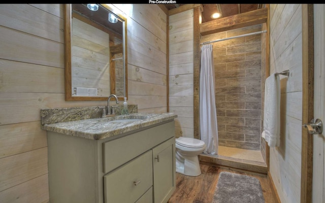 bathroom featuring wooden walls, vanity, wood-type flooring, and walk in shower