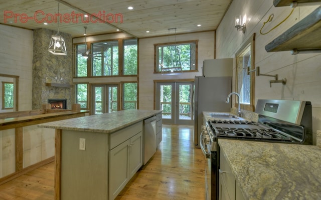 kitchen featuring a center island, french doors, a stone fireplace, light hardwood / wood-style floors, and stainless steel appliances