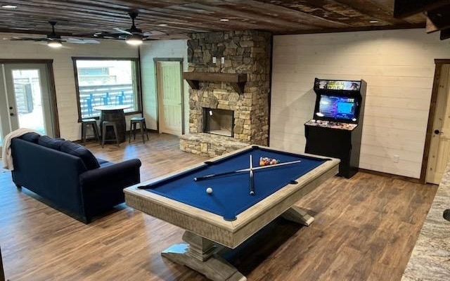 playroom featuring hardwood / wood-style floors, a stone fireplace, and billiards