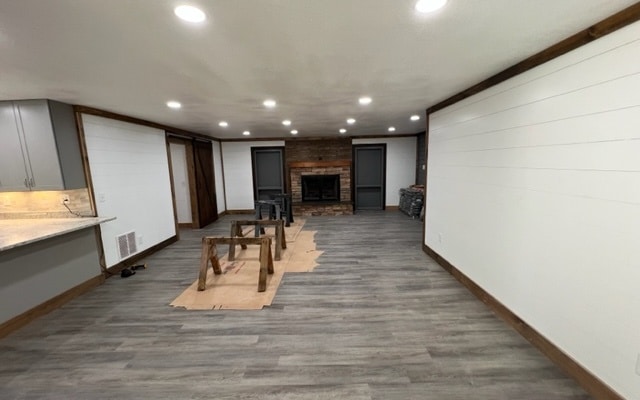 below grade area with wood finished floors, visible vents, baseboards, a fireplace, and recessed lighting