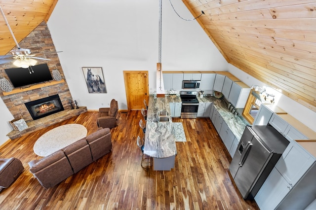 living room with a fireplace, wood ceiling, dark hardwood / wood-style flooring, ceiling fan, and high vaulted ceiling