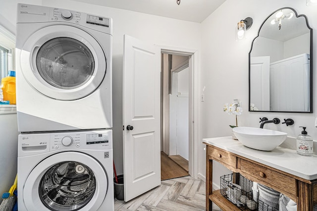 laundry area featuring stacked washer / dryer, sink, and light parquet floors