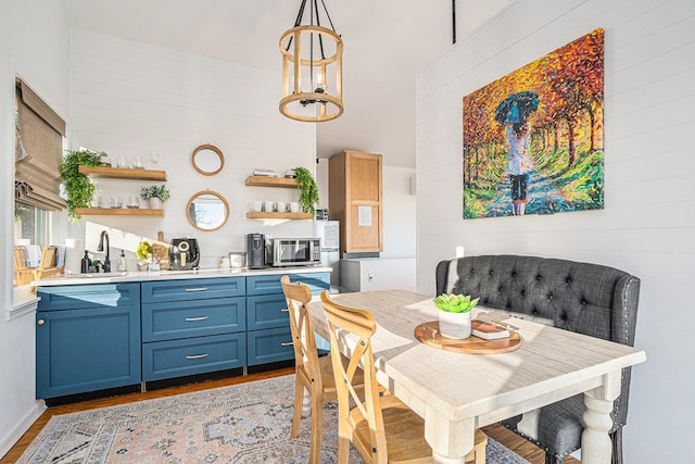 dining room featuring an inviting chandelier, light hardwood / wood-style floors, sink, and a high ceiling