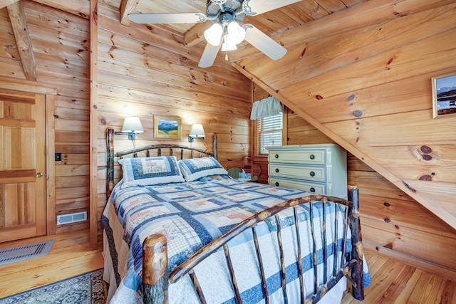 bedroom featuring hardwood / wood-style flooring, visible vents, wooden ceiling, wooden walls, and vaulted ceiling with beams