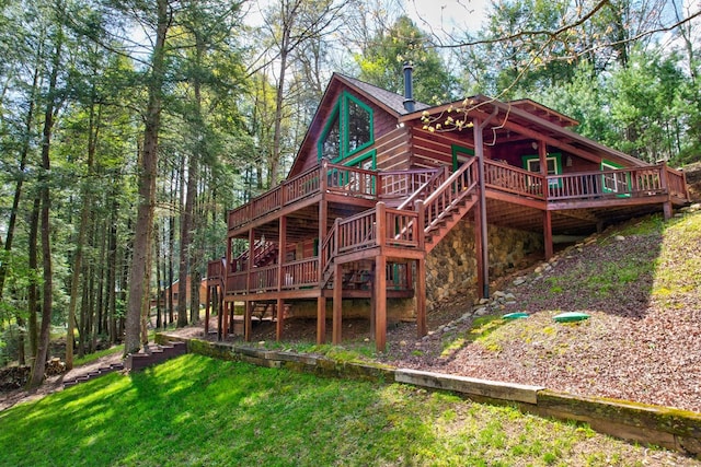 rear view of house featuring a lawn, a wooden deck, and stairs