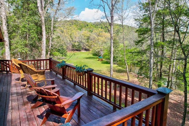 deck with a lawn, a playground, and a view of trees