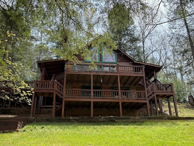 rear view of property featuring a deck, a lawn, and stairs