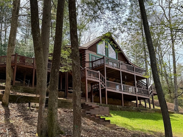 rear view of property featuring a wooden deck, a yard, and stairs