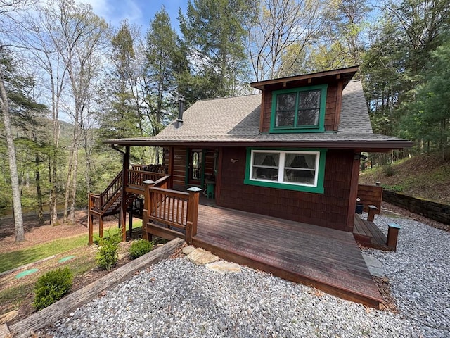 chalet / cabin with a deck and roof with shingles