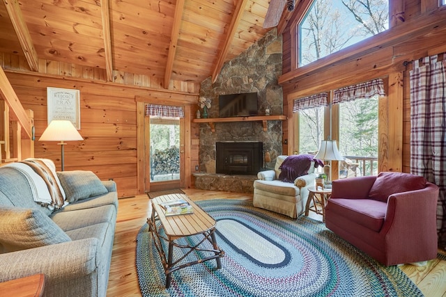 living area with wood ceiling, beam ceiling, wooden walls, a fireplace, and wood finished floors