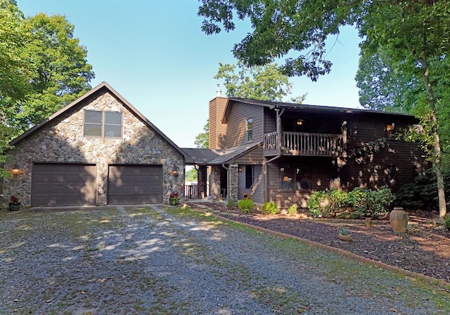 view of front of property with gravel driveway, a chimney, a balcony, a garage, and stone siding