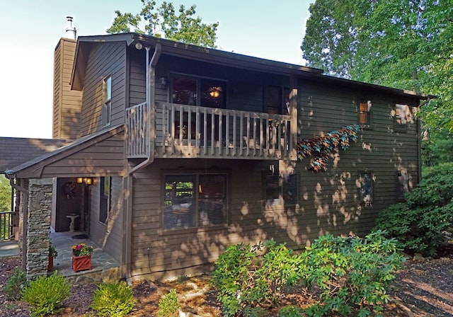 back of property with a balcony, a chimney, and a patio area