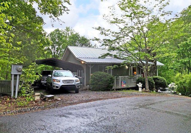 view of side of property with a porch, a carport, driveway, and metal roof