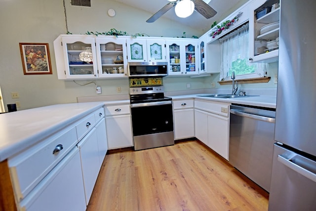kitchen with a sink, appliances with stainless steel finishes, light countertops, and lofted ceiling