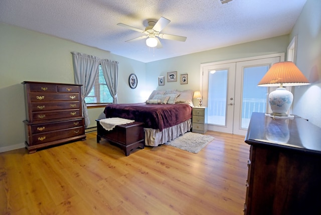 bedroom with french doors, a textured ceiling, light wood-style floors, and a baseboard heating unit