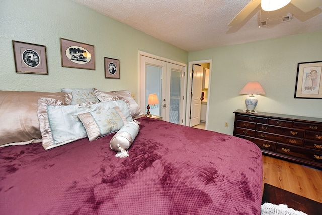 bedroom featuring ceiling fan, a textured ceiling, french doors, wood finished floors, and visible vents