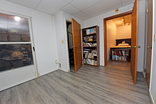 interior space featuring wood finished floors, baseboards, and a drop ceiling