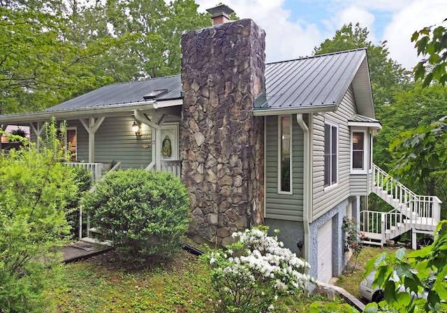 view of property exterior with stairway, a chimney, metal roof, and a garage