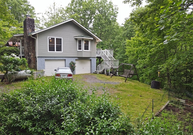 back of property with stairs, a chimney, an attached garage, and driveway