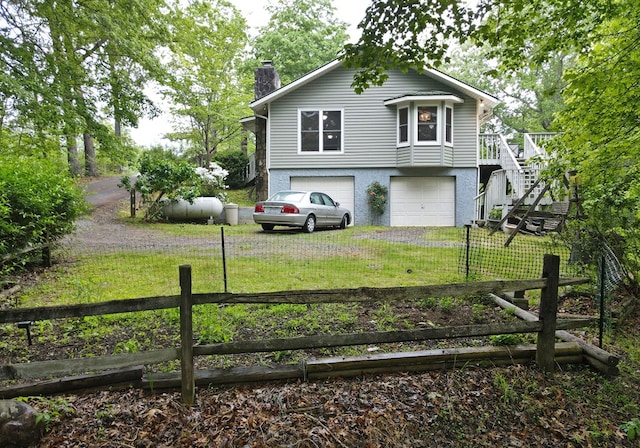 tri-level home with a garage, a front yard, driveway, and a chimney