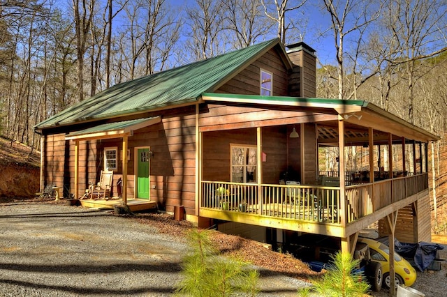 view of front of property featuring driveway, a chimney, and metal roof