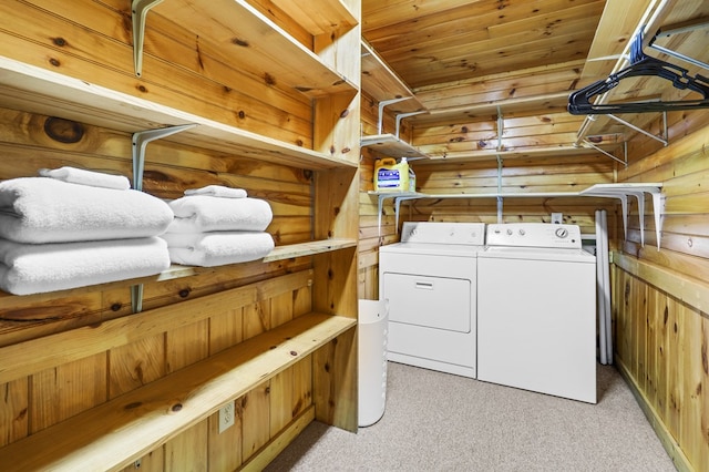 clothes washing area featuring wooden walls, light carpet, wooden ceiling, and independent washer and dryer