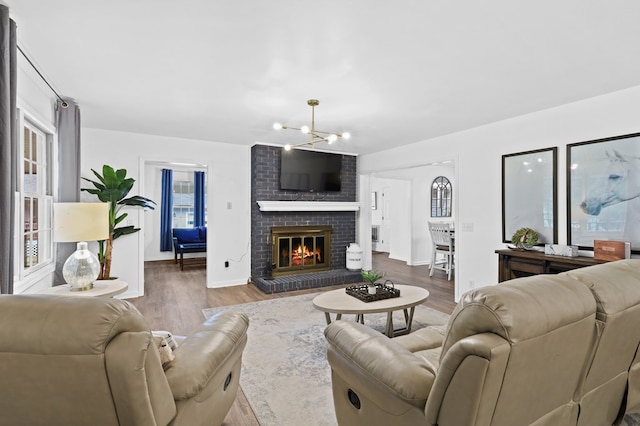 living room with wood-type flooring, a chandelier, and a fireplace