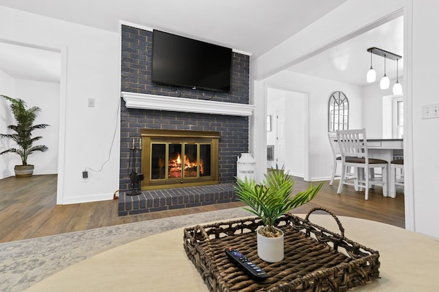 living room with beamed ceiling, wood-type flooring, and a brick fireplace