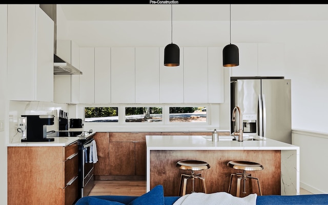 kitchen featuring light hardwood / wood-style flooring, appliances with stainless steel finishes, white cabinetry, hanging light fixtures, and a kitchen island with sink