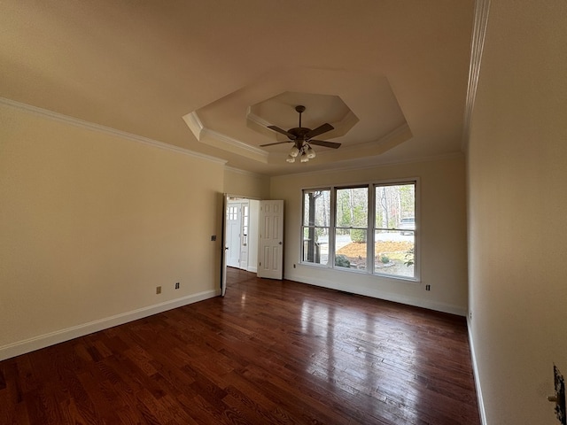 spare room featuring a tray ceiling, dark wood finished floors, and crown molding