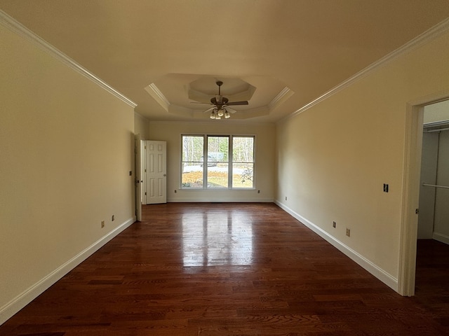 unfurnished room featuring crown molding, baseboards, a raised ceiling, and dark wood-type flooring