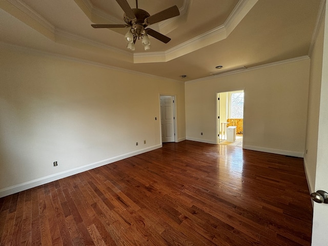 spare room featuring baseboards, a raised ceiling, ceiling fan, ornamental molding, and dark wood-type flooring