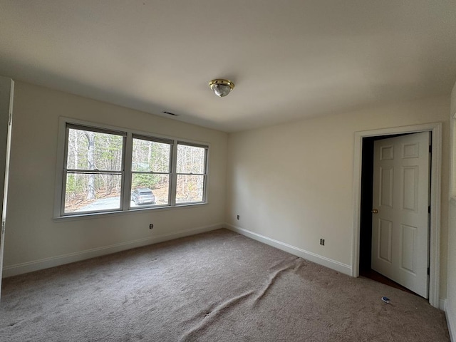 carpeted empty room with visible vents and baseboards