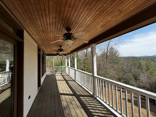 deck with ceiling fan and a forest view