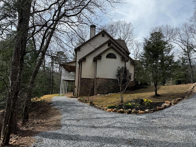 view of home's exterior featuring driveway and a chimney