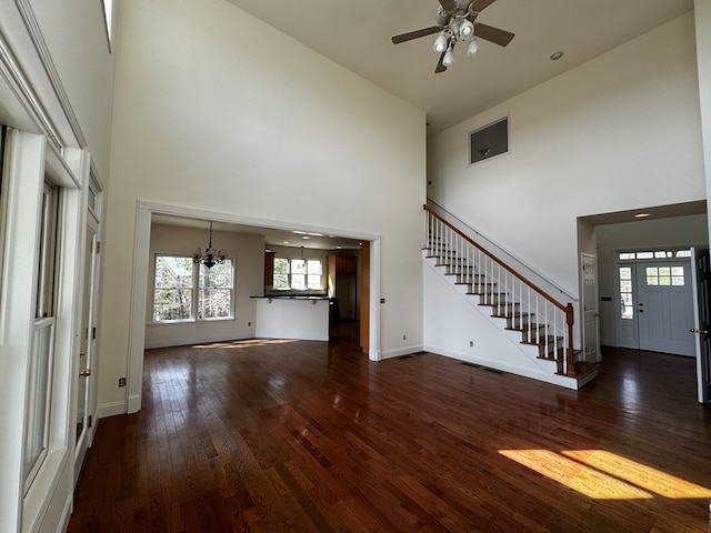 unfurnished living room with stairs, a high ceiling, and hardwood / wood-style flooring