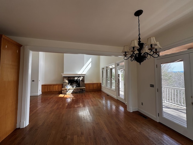 interior space featuring dark wood-style floors, a healthy amount of sunlight, visible vents, and a stone fireplace