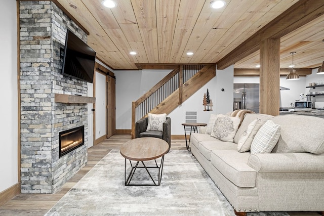 living room featuring wood-type flooring, a stone fireplace, and wooden ceiling