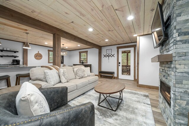 living room with beamed ceiling, wooden ceiling, a fireplace, and light hardwood / wood-style floors