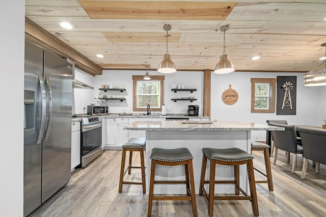 kitchen featuring hanging light fixtures, stainless steel appliances, white cabinets, and light stone countertops