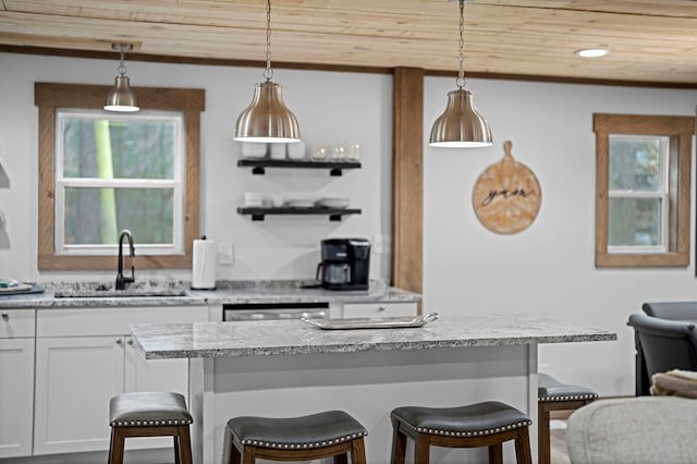 kitchen featuring a kitchen bar, sink, hanging light fixtures, and wooden ceiling