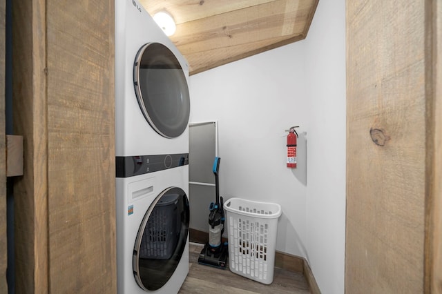 laundry area with stacked washing maching and dryer and hardwood / wood-style floors