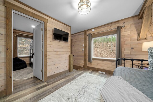 bedroom featuring multiple windows, hardwood / wood-style floors, and wood walls