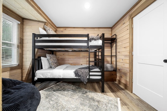 bedroom with hardwood / wood-style flooring and wood walls