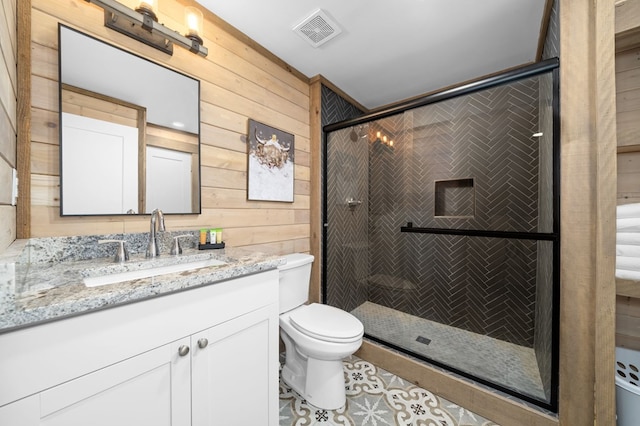 bathroom with vanity, toilet, a shower with shower door, and wood walls