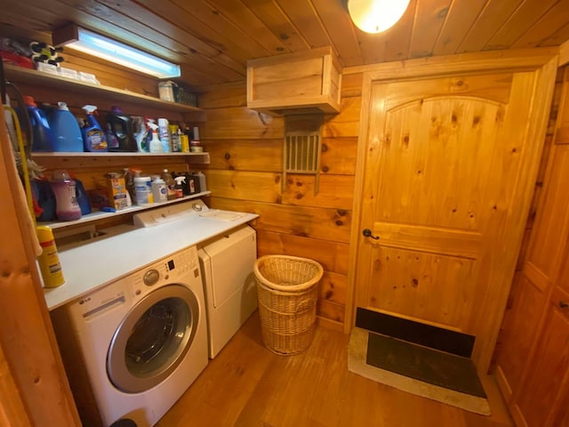 washroom with separate washer and dryer, wooden walls, wood ceiling, and light hardwood / wood-style floors